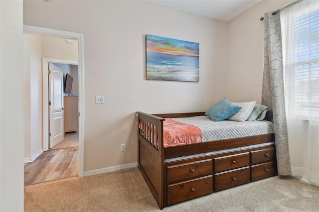 bedroom featuring light colored carpet and baseboards