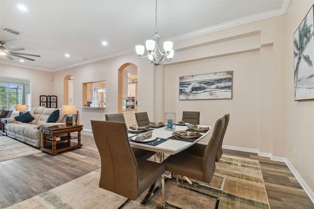 dining area with ceiling fan with notable chandelier, wood-type flooring, and ornamental molding