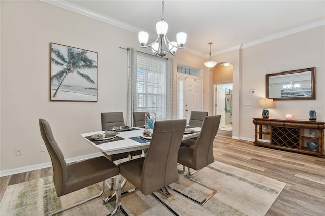 dining space featuring baseboards, wood finished floors, arched walkways, and ornamental molding