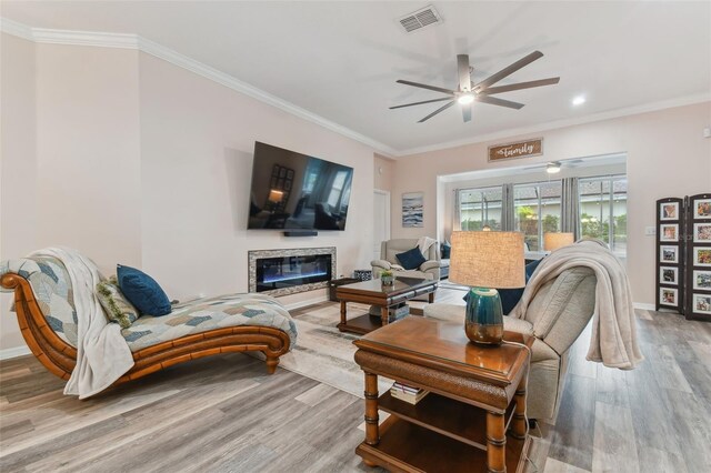 living room featuring ceiling fan, ornamental molding, and hardwood / wood-style flooring