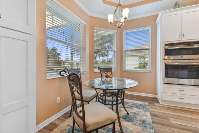 dining space featuring light wood-type flooring, ornamental molding, and a healthy amount of sunlight