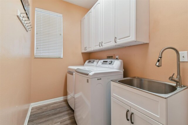 laundry area featuring sink, light hardwood / wood-style floors, cabinets, and washer and dryer