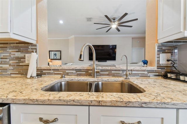 kitchen featuring light stone counters, ornamental molding, white cabinetry, and a sink