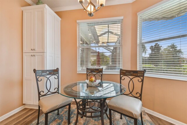 dining space with hardwood / wood-style flooring, crown molding, and a chandelier