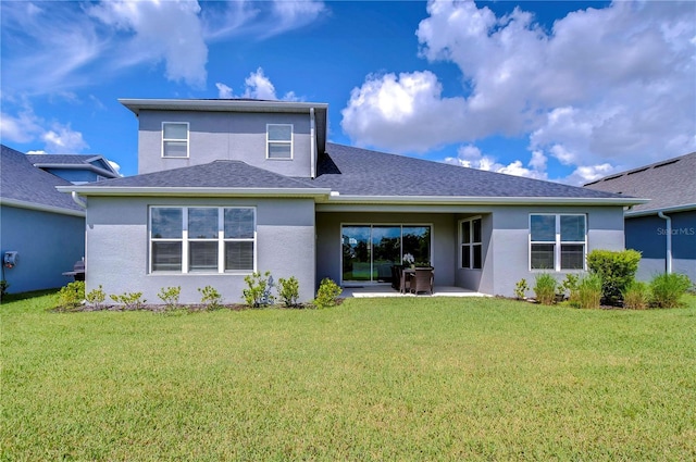 rear view of house with a shingled roof, a lawn, a patio area, and stucco siding