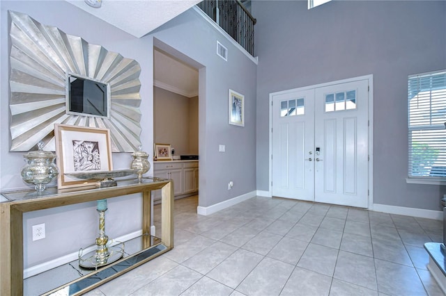 foyer entrance with a high ceiling, visible vents, baseboards, and light tile patterned floors