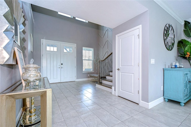 foyer with light tile patterned floors, baseboards, stairway, and ornamental molding