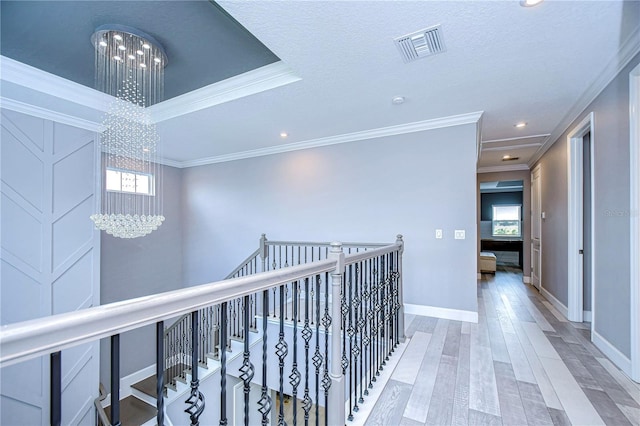 corridor featuring crown molding, visible vents, an upstairs landing, wood finished floors, and a chandelier