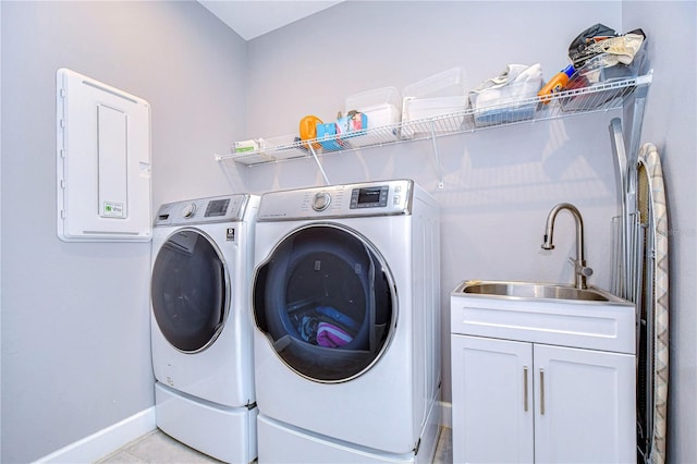 clothes washing area featuring washing machine and dryer, a sink, cabinet space, and baseboards