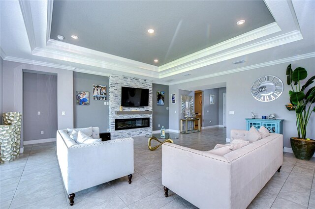 living room featuring ornamental molding, a fireplace, and a tray ceiling