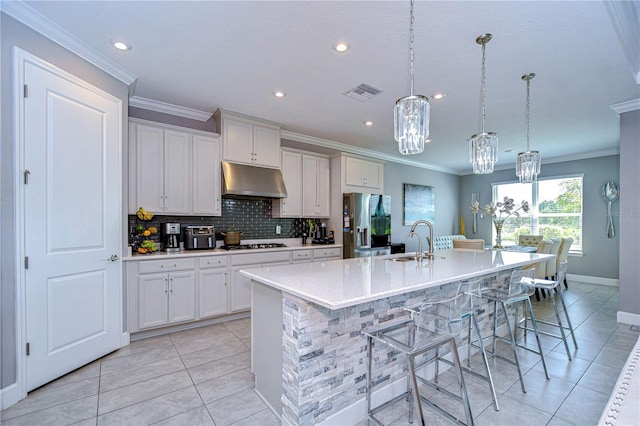 kitchen with visible vents, backsplash, a sink, under cabinet range hood, and stainless steel fridge with ice dispenser