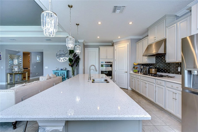 kitchen featuring under cabinet range hood, stainless steel appliances, a sink, visible vents, and tasteful backsplash