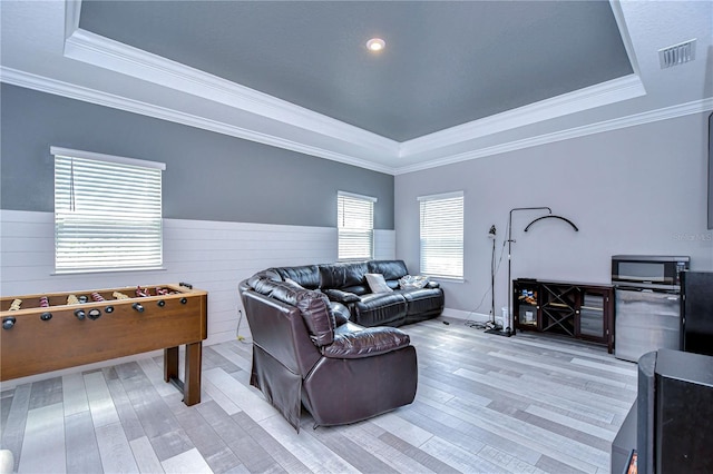 living room with ornamental molding, a tray ceiling, wood finished floors, and visible vents