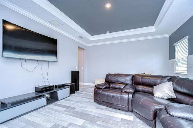 living area featuring light wood-style flooring, baseboards, a raised ceiling, and crown molding