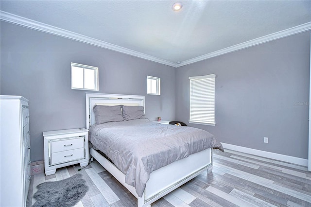 bedroom featuring ornamental molding, light wood-style flooring, and baseboards