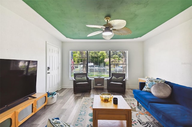 living room with a tray ceiling, hardwood / wood-style flooring, and ceiling fan