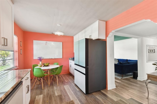 kitchen featuring appliances with stainless steel finishes, hanging light fixtures, light hardwood / wood-style floors, and white cabinetry