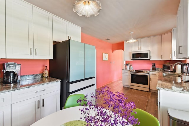 kitchen with white cabinets, stainless steel appliances, sink, and stone counters