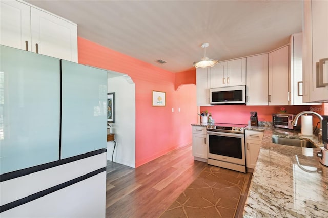 kitchen featuring appliances with stainless steel finishes, light stone counters, white cabinetry, sink, and dark hardwood / wood-style floors