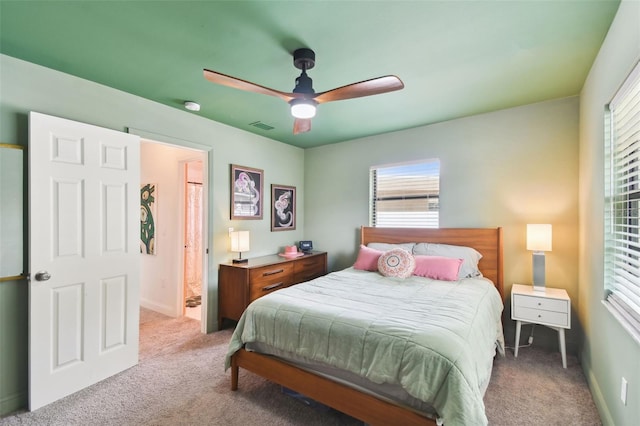 carpeted bedroom featuring ensuite bath and ceiling fan