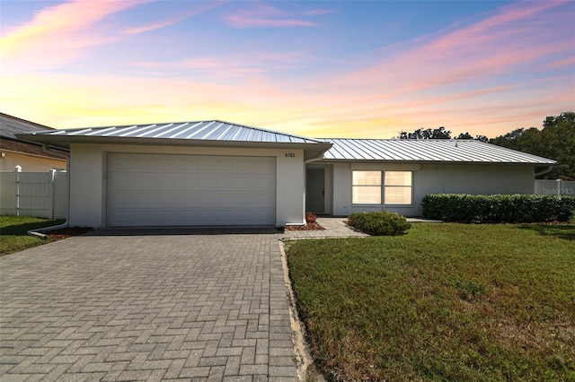 ranch-style home with a garage and a yard