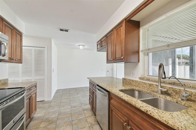 kitchen with light tile patterned flooring, light stone countertops, sink, and stainless steel appliances