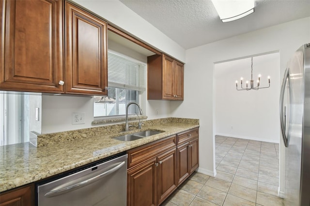 kitchen featuring hanging light fixtures, light stone counters, stainless steel appliances, an inviting chandelier, and sink