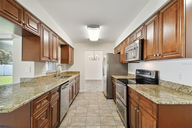 kitchen with light stone counters, a chandelier, sink, kitchen peninsula, and stainless steel appliances