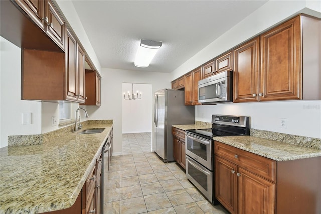 kitchen featuring light stone counters, sink, a textured ceiling, stainless steel appliances, and a notable chandelier