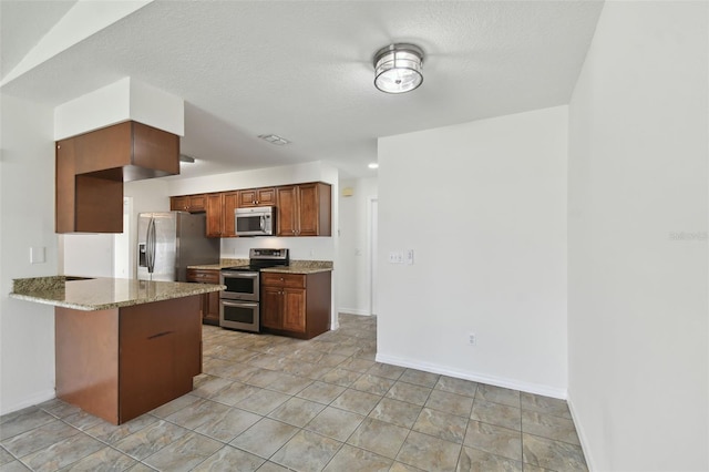 kitchen with a textured ceiling, kitchen peninsula, stainless steel appliances, and light stone counters