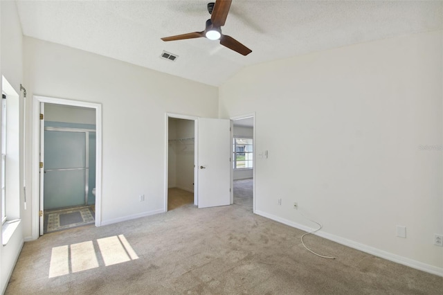 unfurnished bedroom featuring a spacious closet, connected bathroom, a closet, ceiling fan, and light colored carpet