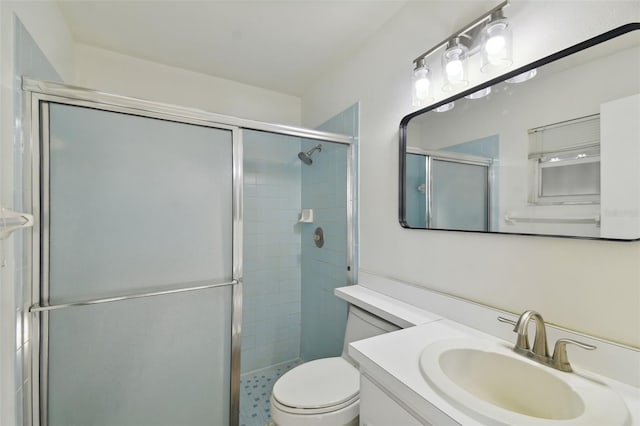 bathroom featuring a shower with door, toilet, and vanity