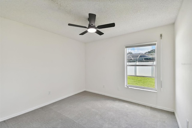 carpeted empty room with ceiling fan and a textured ceiling