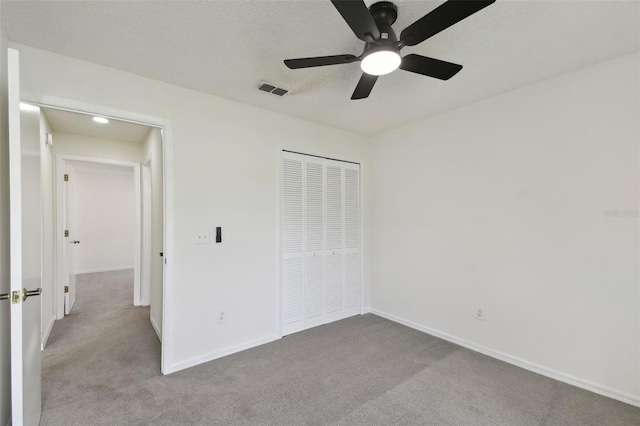 unfurnished bedroom with a closet, ceiling fan, light colored carpet, and a textured ceiling