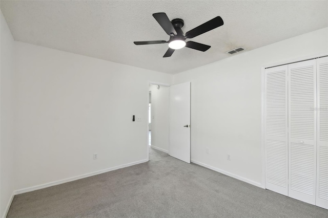 unfurnished bedroom with a textured ceiling, ceiling fan, light colored carpet, and a closet