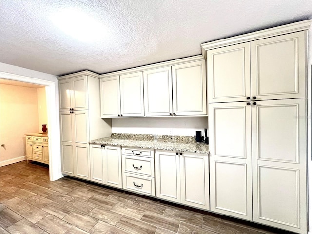 kitchen with light stone countertops, a textured ceiling, and light hardwood / wood-style flooring