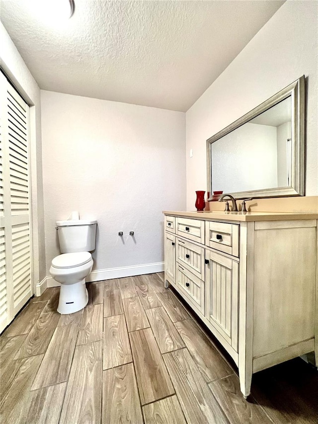 bathroom featuring toilet, vanity, hardwood / wood-style floors, and a textured ceiling