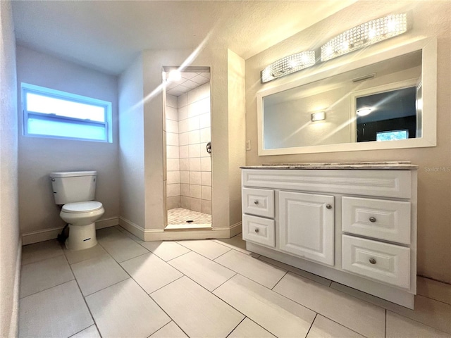 bathroom with toilet, vanity, tile patterned flooring, and a tile shower