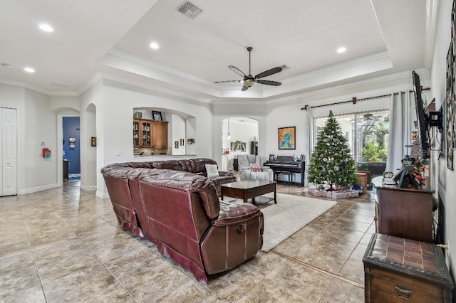 living room featuring crown molding, ceiling fan, and a tray ceiling