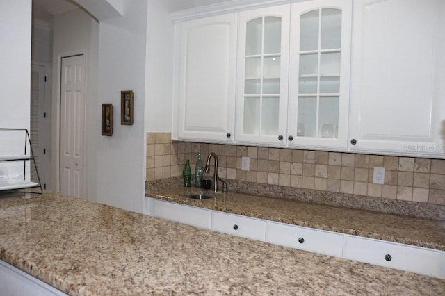 kitchen with white cabinetry, sink, and light stone counters