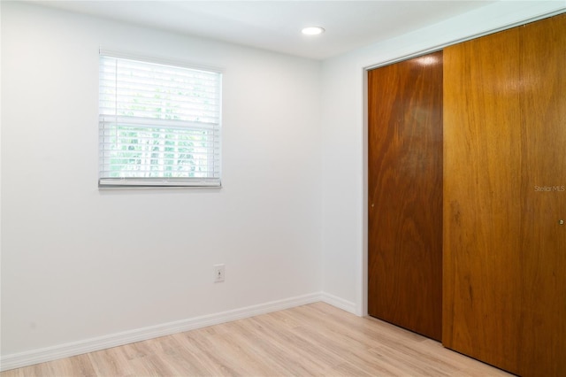 unfurnished bedroom with light wood-type flooring and a closet