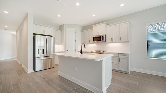 kitchen featuring tasteful backsplash, an island with sink, stainless steel appliances, and a healthy amount of sunlight