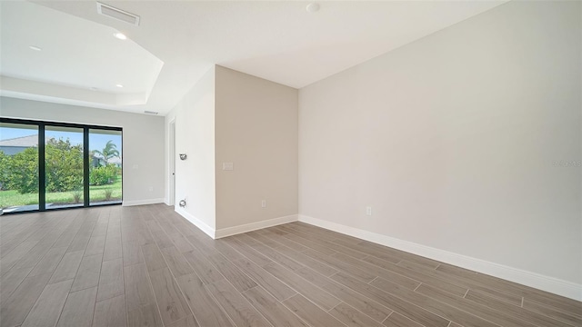 empty room with a tray ceiling and hardwood / wood-style floors