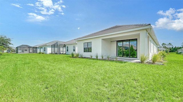 rear view of house featuring a yard and glass enclosure