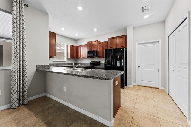 kitchen with black appliances, light tile patterned floors, kitchen peninsula, and sink