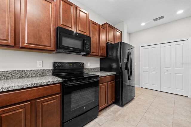 kitchen featuring black appliances, light stone counters, and light tile patterned floors