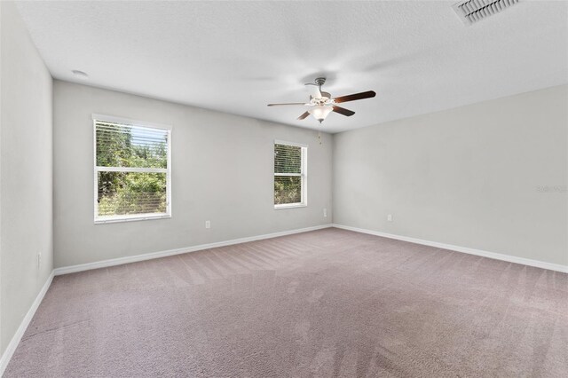 unfurnished room with a textured ceiling, ceiling fan, and carpet floors