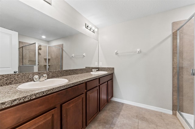 bathroom featuring a shower with door, vanity, tile patterned flooring, and a textured ceiling