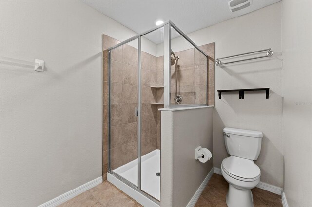 bathroom with tile patterned flooring, toilet, and a shower with door