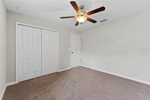 unfurnished bedroom with carpet, a closet, and ceiling fan